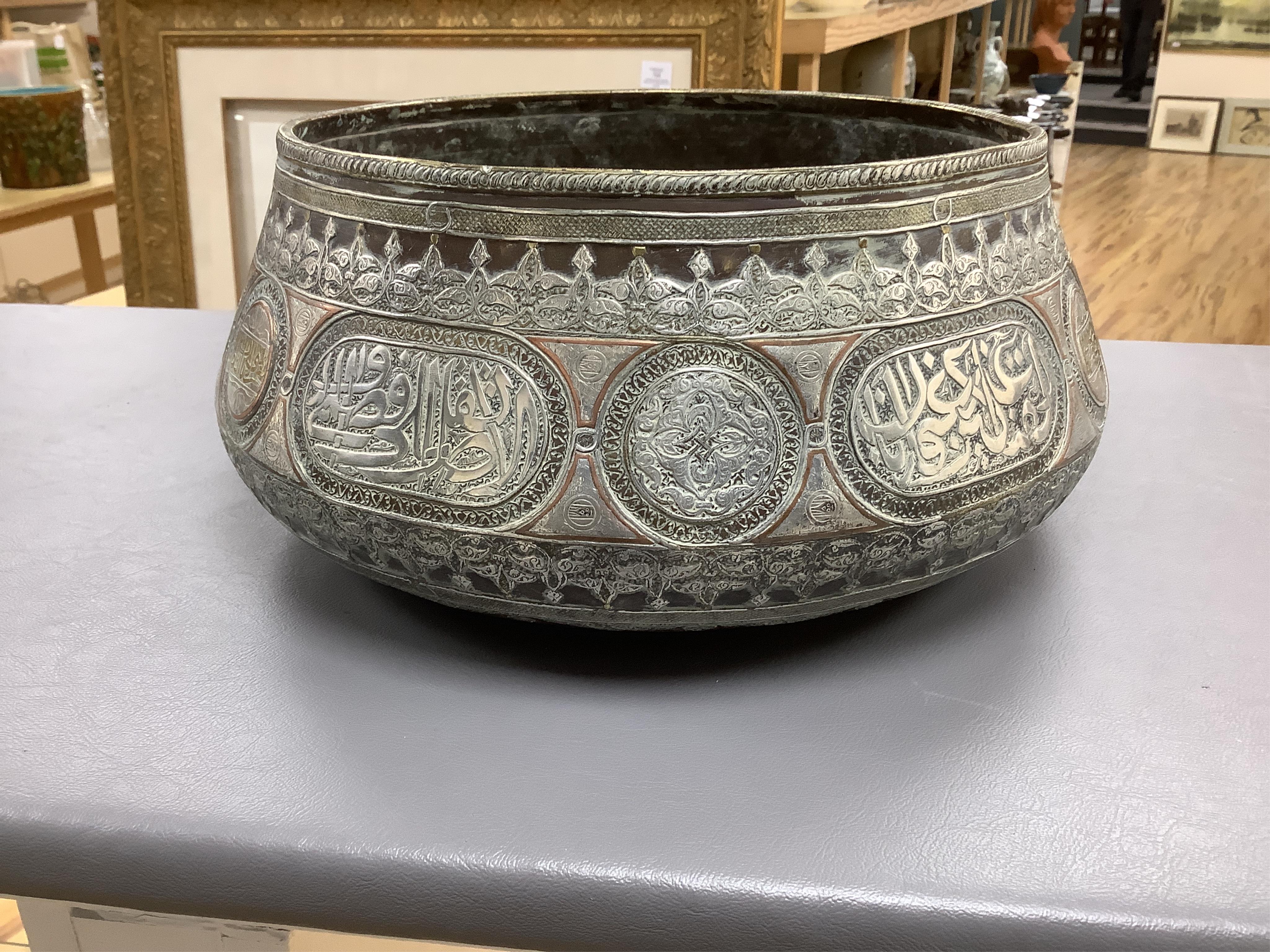 A late 19th century Mamluk style brass basin inlaid with silver and copper decoration, 29cm diameter